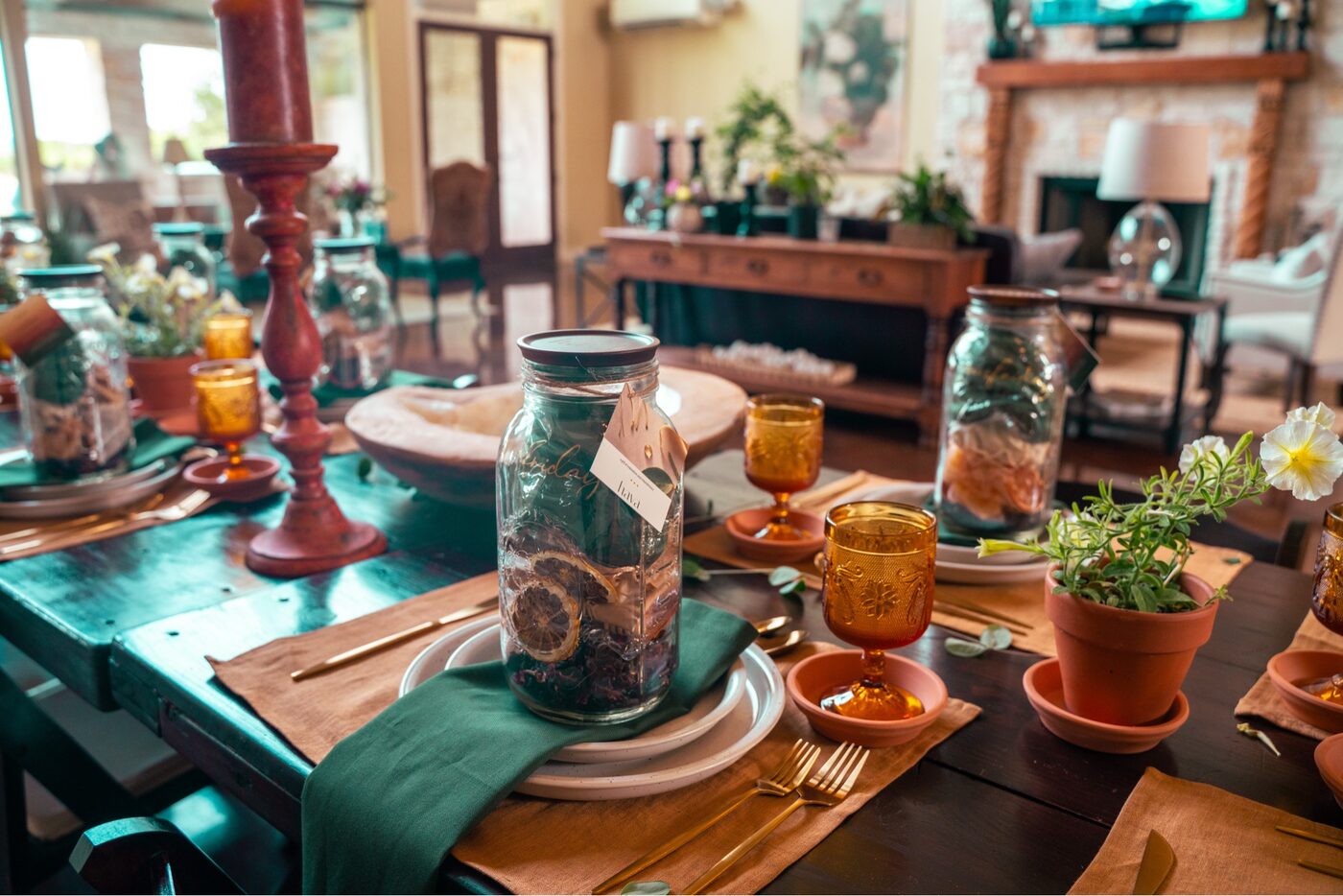 The long retreat table set by hand with mason jars, green linen napkins, amber glasses, and terracotta pots.