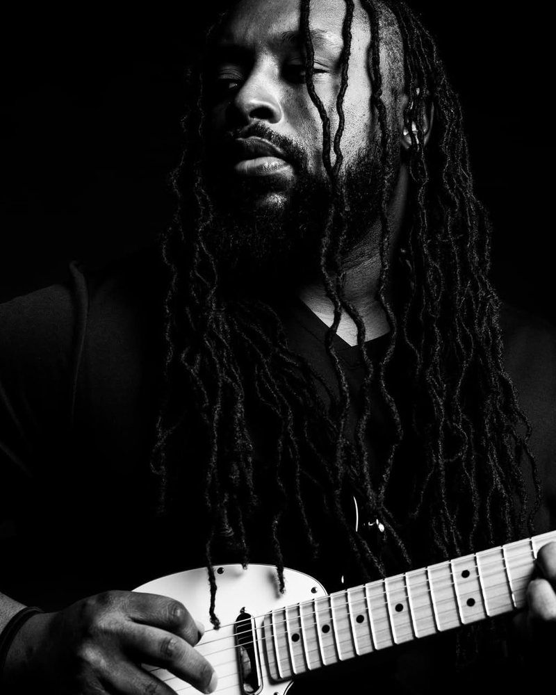 Juston Hargrove with his guitar, in black and white.
